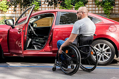 Man in wheelchair in front of adapted car