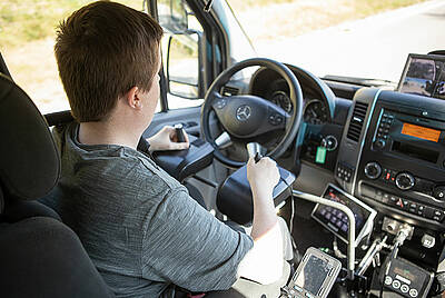 Man driving a vehicle with joystick for steering, gas and brake